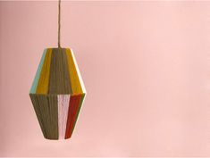 a multicolored wooden ornament hanging from a string on a pink wall