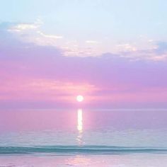 the sun is setting over the ocean with pink and blue sky in the back ground