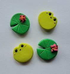 four decorated cookies sitting on top of a white table next to green leaves and flowers