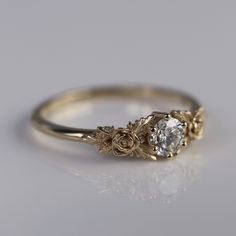 a gold ring with a white diamond in the center on a gray background, close up