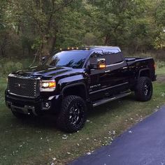 a black truck is parked on the side of the road in front of some trees