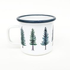 a white and blue mug with trees painted on the inside is sitting against a white background