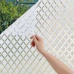 a person is holding up a piece of paper to the side of a white wall