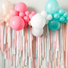 balloons, streamers and tassels are arranged on the wall for a party