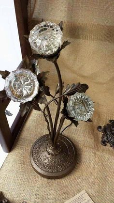 three metal flowers in a vase on a table next to a plaque and other items