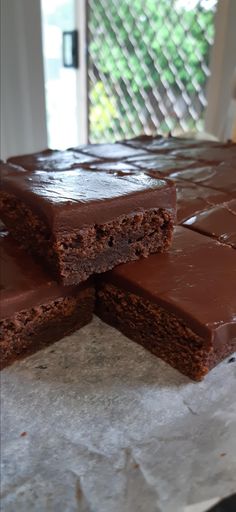 three pieces of chocolate cake sitting on top of paper