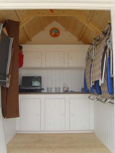 the inside of a small kitchen with white cabinets and wood flooring on the walls