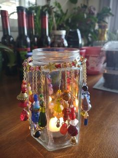 a glass jar filled with lots of different colored beads and chains on top of a wooden table