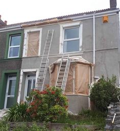 a house that has been boarded up and is being worked on by a man with a ladder