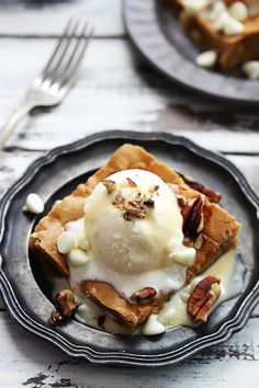 two plates with waffles, ice cream and nuts on them next to a fork