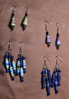 several different types of earrings are displayed on a brown surface with white and blue beads