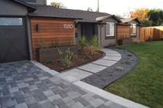 a house with a driveway in front of it and landscaping on the other side of the house