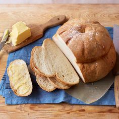 a loaf of bread sitting on top of a blue napkin next to butter and a knife