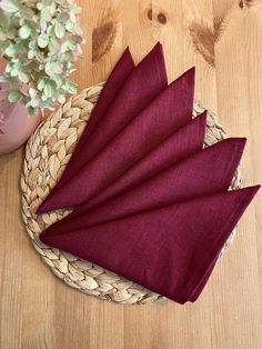 six napkins in a basket on a wooden table next to a potted plant