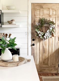 a wooden door with a wreath on top of it and candles in front of it