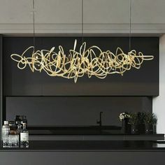 a modern kitchen with black counter tops and white walls, along with an artistic chandelier hanging from the ceiling