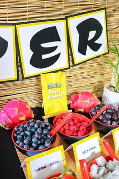 a table topped with bowls filled with fruit and veggies next to signs that spell out er