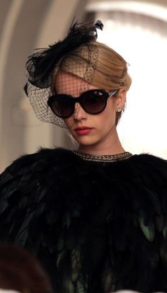 a woman wearing sunglasses and a hat with feathers