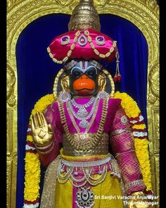 an elaborately decorated puppet is displayed in front of a blue curtain and gold frame