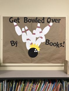 a bulletin board with bowling pins on it in front of a bookcase filled with books