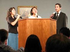 two people standing at a podium with microphones in front of them and an audience