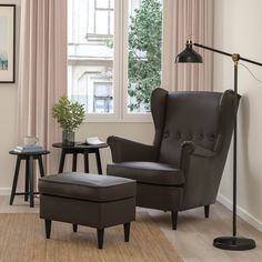 a living room with a chair, ottoman and table in front of a large window