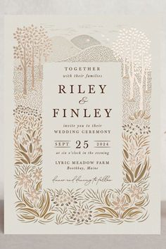 a wedding card with gold foil on the front, and an image of trees in the background