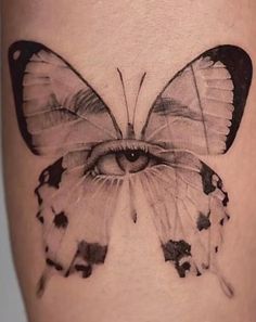 a black and white photo of a butterfly on the side of a woman's leg