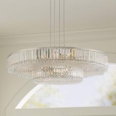 a crystal chandelier hanging from the ceiling in a room with white walls and windows