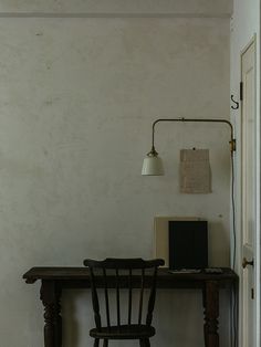 a desk with a laptop on it next to a lamp and chair in a room