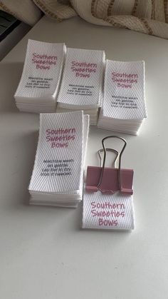 four pieces of white paper with pink clips attached to them sitting on a table next to a pillow