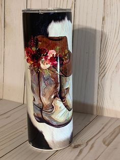 a cowboy boot with flowers painted on it is sitting next to a wooden wall,