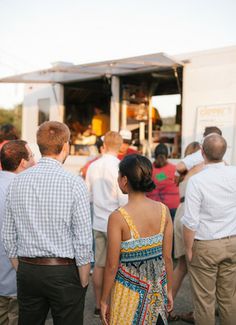 a group of people standing in front of a food truck at an outdoor event or gathering