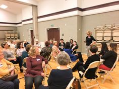 a group of people sitting in chairs talking to each other