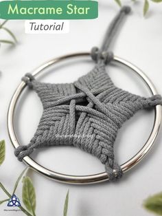 a crocheted star ornament hanging from a metal ring with leaves around it