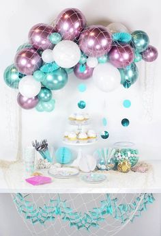 a table topped with lots of balloons and cake