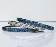 Vintage set of three natural pave set sapphire bangle bracelets.  Metal: black rhodium plated sterling silver  Gemstones: Pave set round brilliant cut blue and white natural sapphire. Each bracelet has approximately 540 sapphires which are individually set in 4 prongs. The sapphires measure approximately 1.5mm for a total carat weight of 14 carats per bracelet and 42 carats for all three bracelets combined.  Size: 63mm inner diameter  Measurements: Each bracelet measures 6mm wide Weight: 67 gram Blue Fine Jewelry Bracelet With Single Cut Diamonds, Fine Jewelry Blue Round Bangle, Elegant Blue Diamond Bangle, Luxury Sapphire Bangle Bracelet, Blue Multi-stone Bangle Jewelry, Luxury Blue Gemstone Bangle, Blue Multi-stone Bangle, Elegant Sapphire Colored Hand-strung Beaded Bracelets, Sapphire Bangle