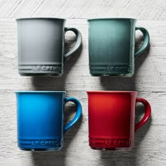 four different colored cups sitting on top of a wooden table