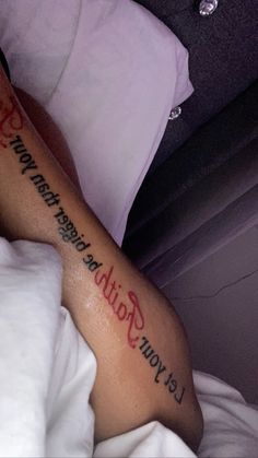 a person laying in bed with a tattoo on their arm that says let your faith be