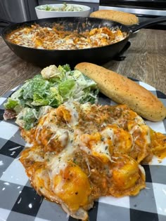 some food is sitting on a checkered tablecloth and next to two skillets