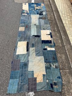 an old patchwork rug is laying on the side of the road next to a curb