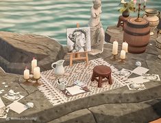 a table with candles, pictures and other items on it next to the water's edge