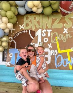 two children and an adult posing for a photo in front of a football themed backdrop