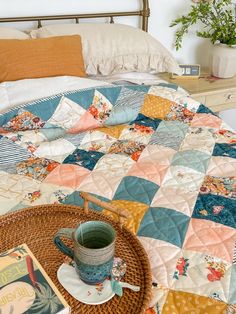 a bed with a quilt and cup on it