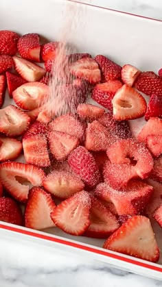 strawberries are being sprinkled with sugar in a baking dish