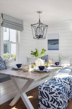 a dining room table with blue and white decor on it, along with matching chairs