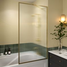 a bathroom with two sinks and a bathtub next to a plant in a vase