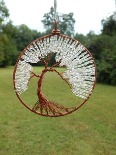 a wire tree hanging in the middle of a field