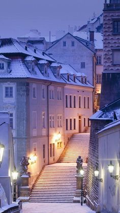 an alley way with snow on the ground and several buildings in the background at night