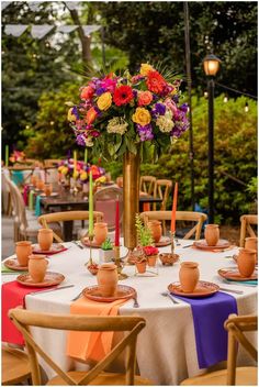 a table set up with flowers and candles for an outdoor dinner or party in the garden